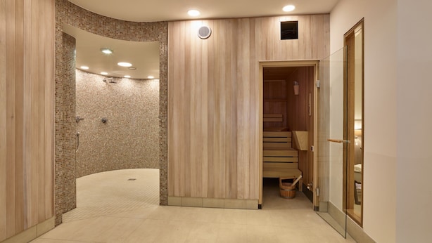 Un área de spa moderna con ducha curva, paneles de madera y sauna de madera.