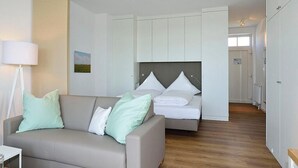 Un dormitorio moderno con una cama, un sofá y una mesita de noche.
