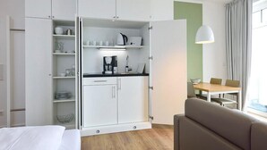 Una habitación de hotel moderna con kitchenette, comedor y sofá.