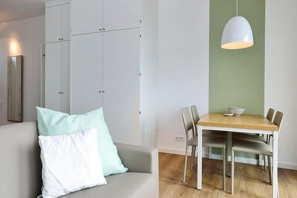 Una sala de estar moderna con un sofá, una mesa de comedor con sillas y una lámpara colgante.