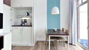 A modern kitchen with white cabinets, a coffee machine, and a dining area with a table and chairs.