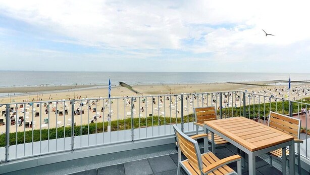 A balcony with a view of a beach and the sea.