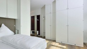 Un dormitorio moderno con cama, armario blanco y vestidor.