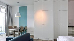 Une chambre d’hôtel moderne dotée d’une grande armoire, d’un coin repas avec une table et des chaises, et d’un canapé.
