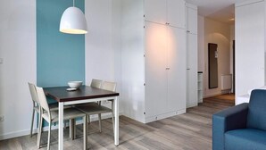 Une pièce moderne et bien éclairée, comprenant une table à manger, des chaises, un mur d’accent bleu et une armoire.