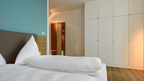 A modern hotel room with a large bed, a wardrobe, and a mirror. - Modernes Apartment an der See mit Westbalkon, Meerblick und Saunabereich im Haus (Nordseeheilbad Wangerooge)