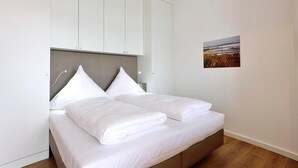 A bedroom with a bed, white headboard, and a wall-mounted picture.