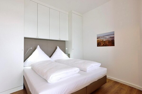 Ein Schlafzimmer mit einem Bett, einem weißen Kopfteil und einem an der Wand befestigten Bild.