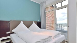 Ein modernes Hotelzimmer mit einem Bett, einem Nachttisch und einem großen Fenster mit Blick auf die Stadt.