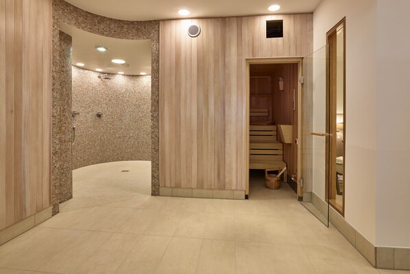 A modern spa area with a curved shower, wooden panel walls, and a wooden sauna.