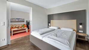 Moderni hotellihuone, jossa on suuri sänky, sohva ja sohvapöytä.
