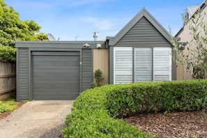 A modern house with a grey garage, a covered driveway, and a well-maintained hedge.
