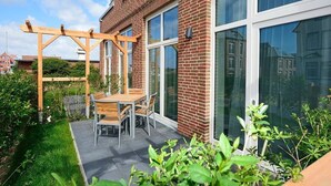 Un patio con una pérgola de madera y una mesa con sillas.