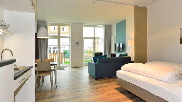 Una habitación de hotel moderna con una cama grande, un sofá, un comedor y una kitchenette.