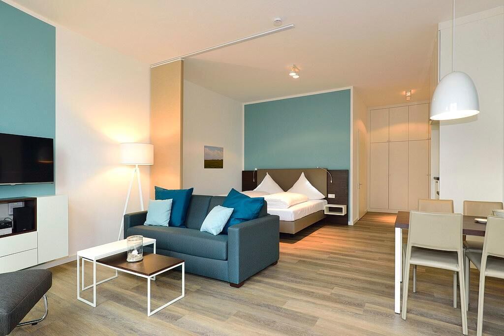 Une chambre d’hôtel moderne équipée d’un canapé, d’un lit, d’une table à manger et d’un téléviseur.