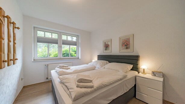 A bedroom with a bed, bedside table, and a window.
