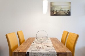 Una mesa de comedor con un salvamantel de periódico, cuatro sillas amarillas y un bol de vidrio en el centro.