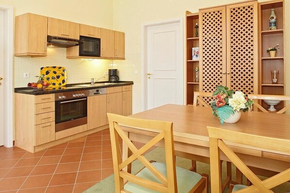 Una cocina compacta con armarios de madera, un microondas, una estufa y un comedor con mesa y sillas.