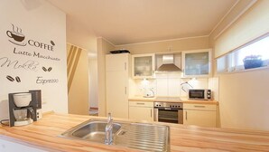 A modern kitchen with a wooden countertop, stainless steel sink, and appliances including a coffee maker, microwave, and oven.