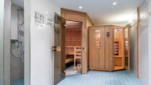 Ein modernes Badezimmer mit Dusche, einer Holzsauna und einem gefliesten Boden.