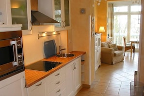 Une cuisine compacte équipée d’un four à micro-ondes, d’une cuisinière et d’un évier. Un coin repas avec une table et des chaises est également disponible.