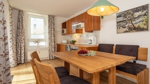 Una cocina moderna con armarios de madera, una mesa de comedor con sillas, una ventana con cortinas y un cuadro en la pared.