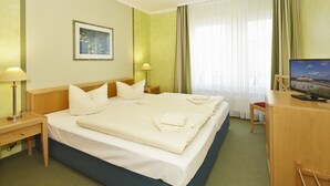 A hotel room with a large bed, two bedside tables, a TV, and a painting on the wall.