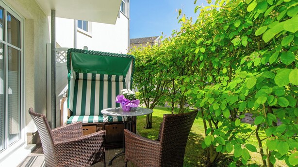 An outdoor patio with wicker furniture, a table, and a green-striped chair.