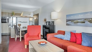 A modern living room with a red sofa, a wooden coffee table, and a dining area with a white table and chairs.