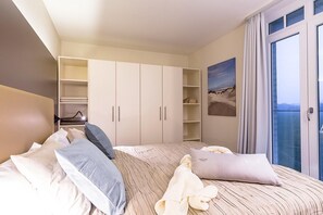 A bedroom with a bed, a wardrobe, a shelf unit, and a balcony with a view. - Schönes Nordsee-apartment mit Sauna, Sonnigem Balkon und Wunderschönem Landblick (Nordseebad Wremen)