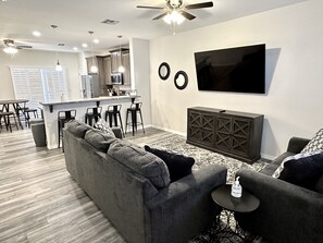 Relax in a spacious living area with a large sofa, flat-screen TV, and bar seating.