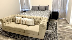A bedroom with a large bed, a sofa, and two nightstands. - Newly Built Home Close to River (Bullhead City)