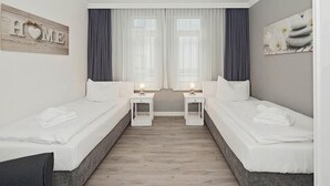 Una habitación de hotel con dos camas individuales, una mesita entre ellas y una silla.