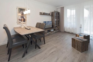Una sala moderna con una mesa de comedor, sillas, un televisor y un aparador.