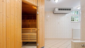 Una sala de sauna con bancos de madera, piso de baldosas y radiador blanco.