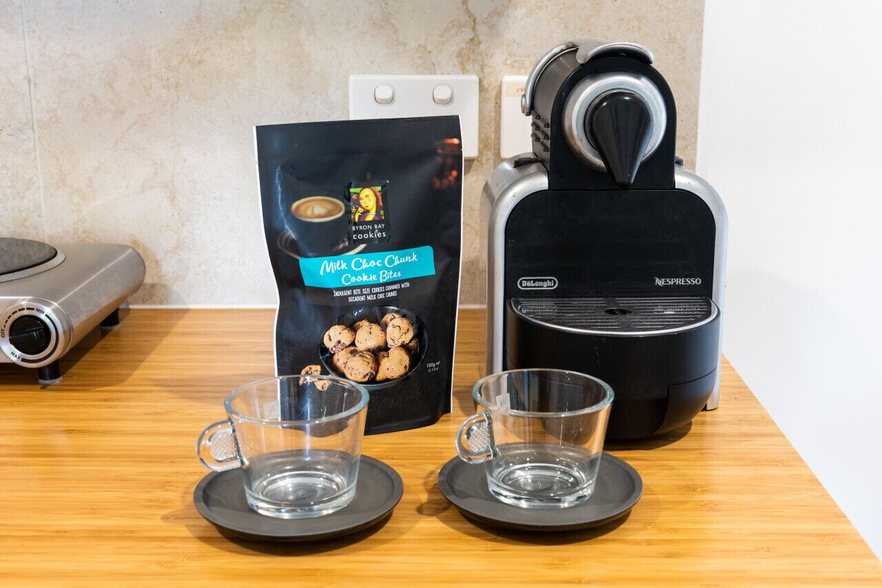 Una cucina con una macchina del caffè, due tazze e un sacchetto di biscotti.