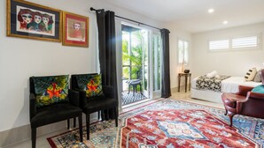 A living room with a black sofa, a patterned rug, and two framed artworks on the wall. - Contemporary Studio in the heart of Paddington (Paddington)