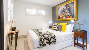 A hotel room with a bed, a painting, a lamp, and a small table. - Contemporary Studio in the heart of Paddington (Paddington)