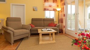 Una sala de estar con dos sofás, una mesa de centro, una lámpara y vistas al exterior a través de un ventanal corredera.