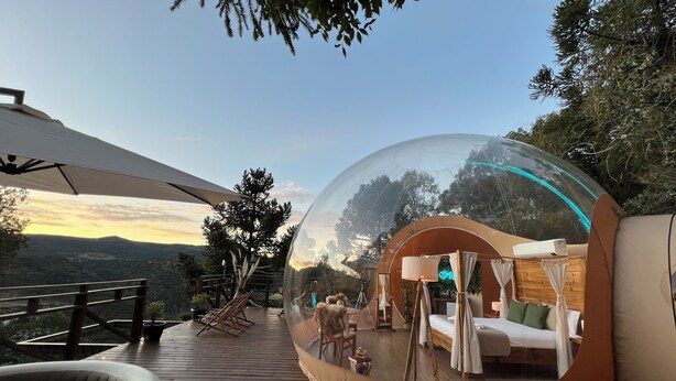 A transparent dome with a bed and a wooden deck.