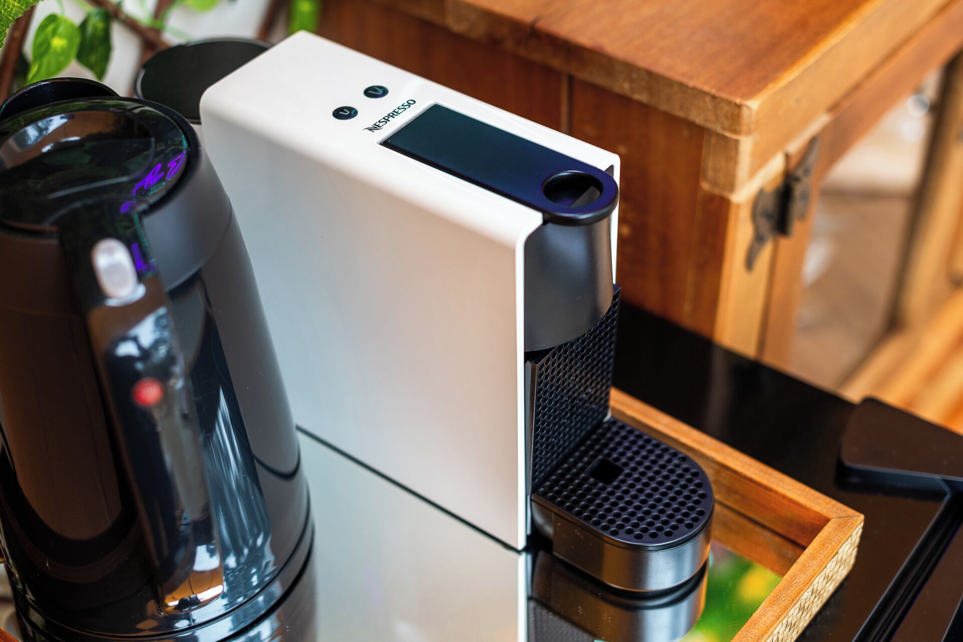 En hvid Nespresso-kaffemaskine med en sort kaffekande ved siden af.