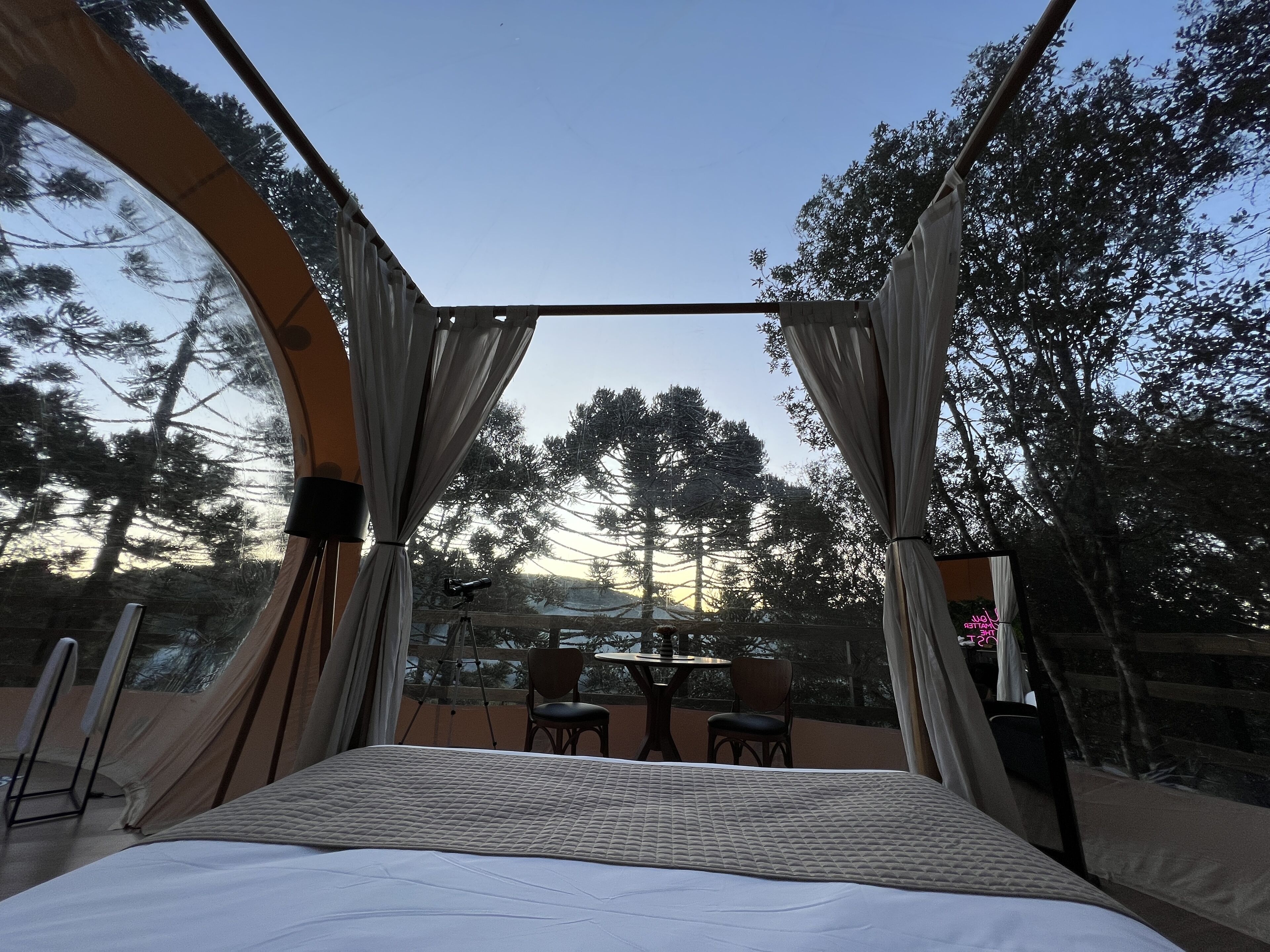 A room with a large bed, a telescope, and a balcony with chairs and a table.