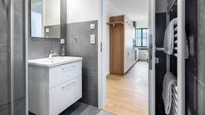 Une salle de bain moderne avec un meuble-lavabo blanc, un grand miroir et un porte-serviettes.