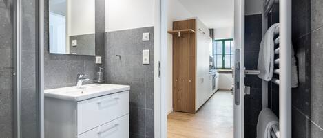 A modern bathroom with a white vanity, a large mirror, and a towel rack.