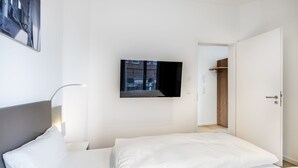 Une chambre d’hôtel avec un lit, un téléviseur fixé au mur et une porte donnant sur un placard.