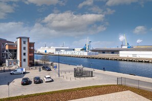 A waterfront area with a parking lot, a pedestrian walkway, and a river.
