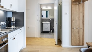 Una cocina moderna con gabinetes blancos, una estufa de acero inoxidable y una cafetera.