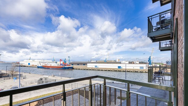 Vista desde un balcón con vista al frente marítimo, con un muelle, una grúa y un edificio con balcón.