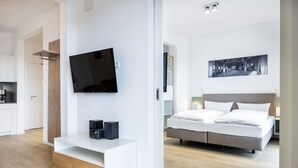 Un dormitorio moderno con una cama, un televisor montado en la pared y un cuadro sobre la cama.