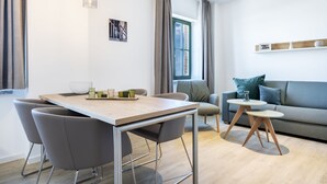 Una sala moderna con una mesa de comedor de madera, sillas grises, un sofá gris y una mesita redonda de vidrio.